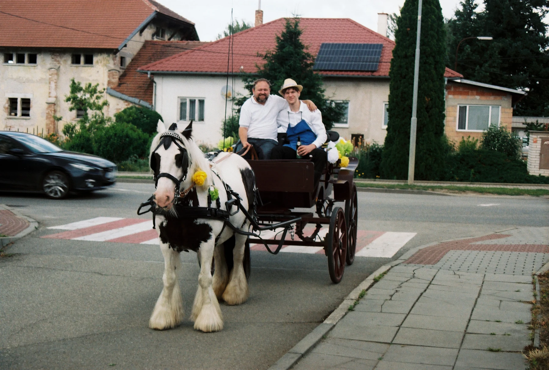Koňský povoz s cestujícími na návsi