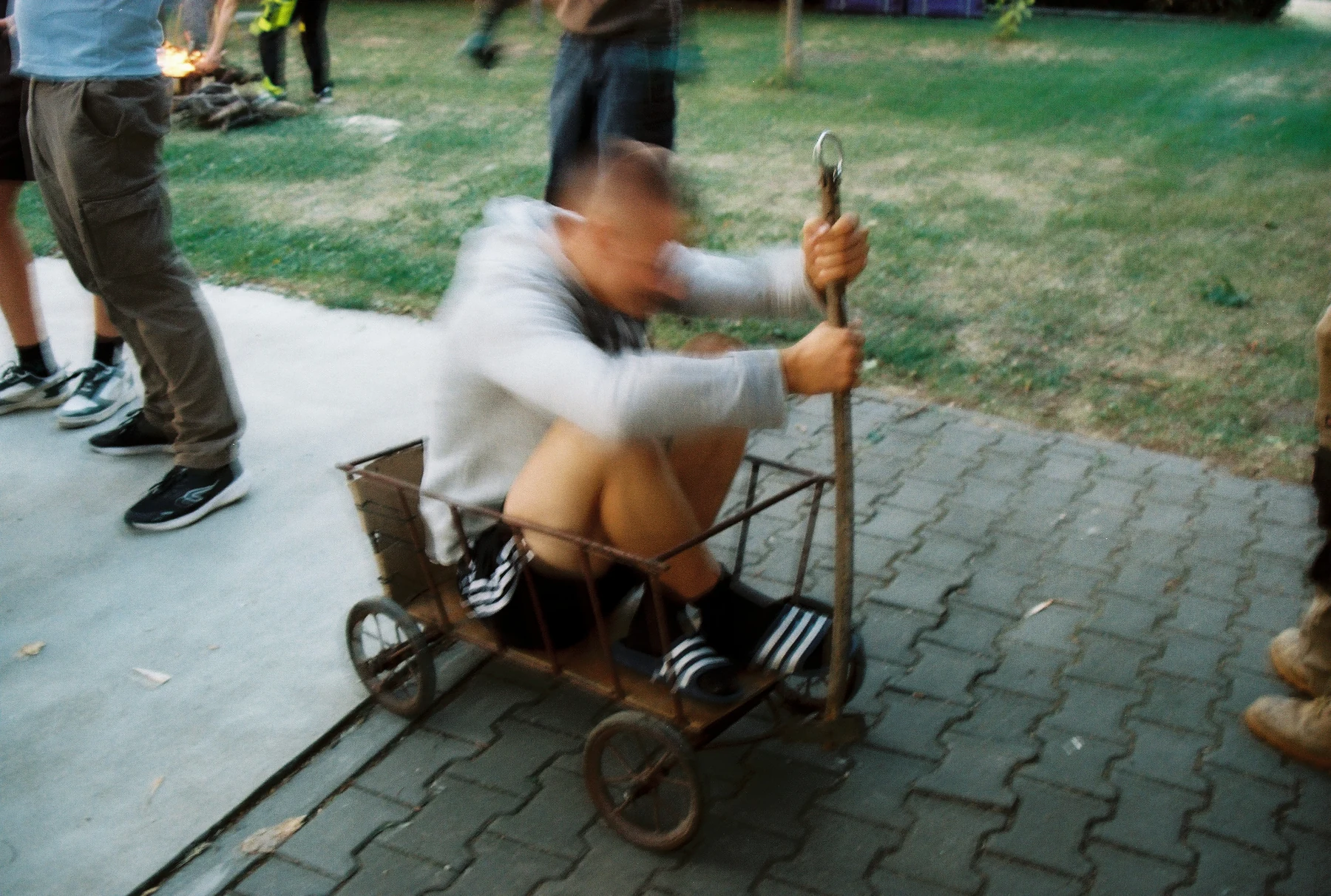 Muž sedí na vozíku na dlážděném dvoře
