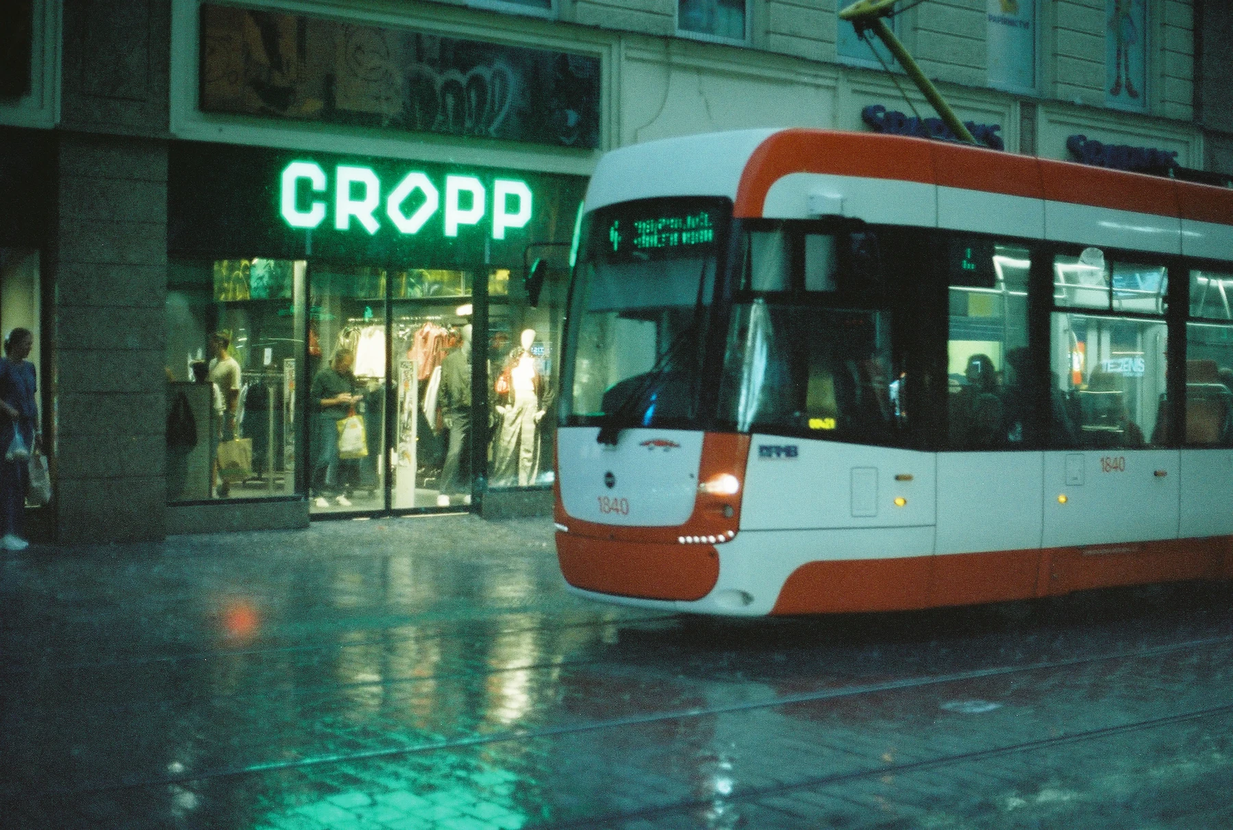 Tramvaj před osvětleným obchodem